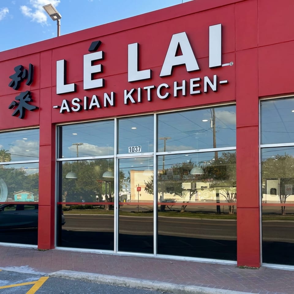 Red storefront for LÉ LAI Asian Kitchen with large windows, glass entrance, and an open sign.